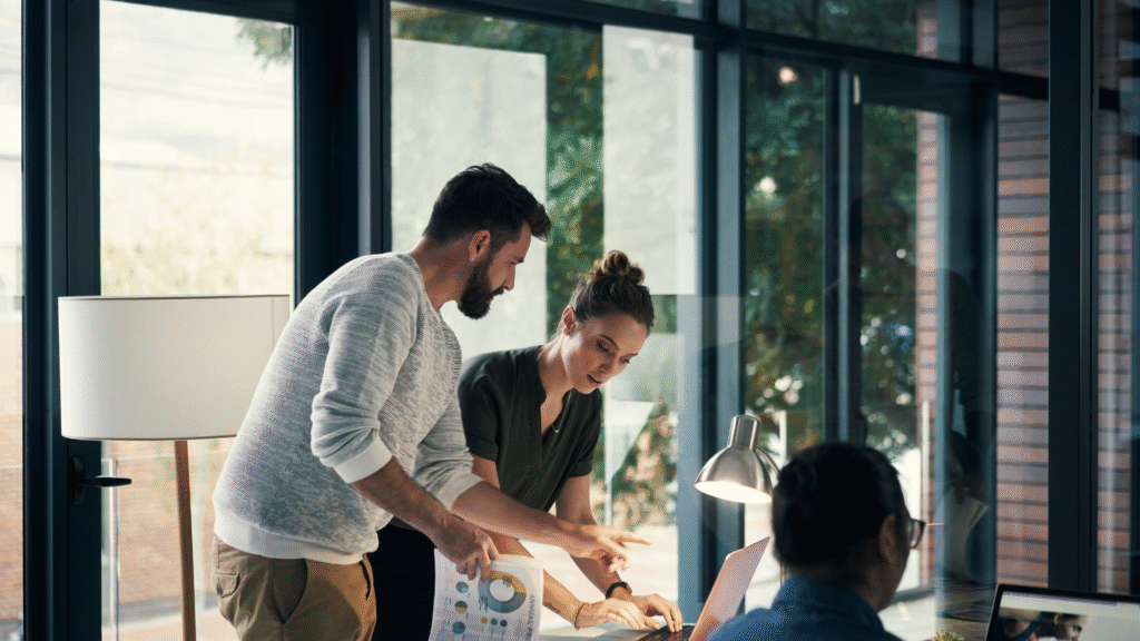 Duas pessoas trabalhando em um escritório, olhando para algo. Para demonstrar como conciliar trabalho CLT com a criação de conteúdo