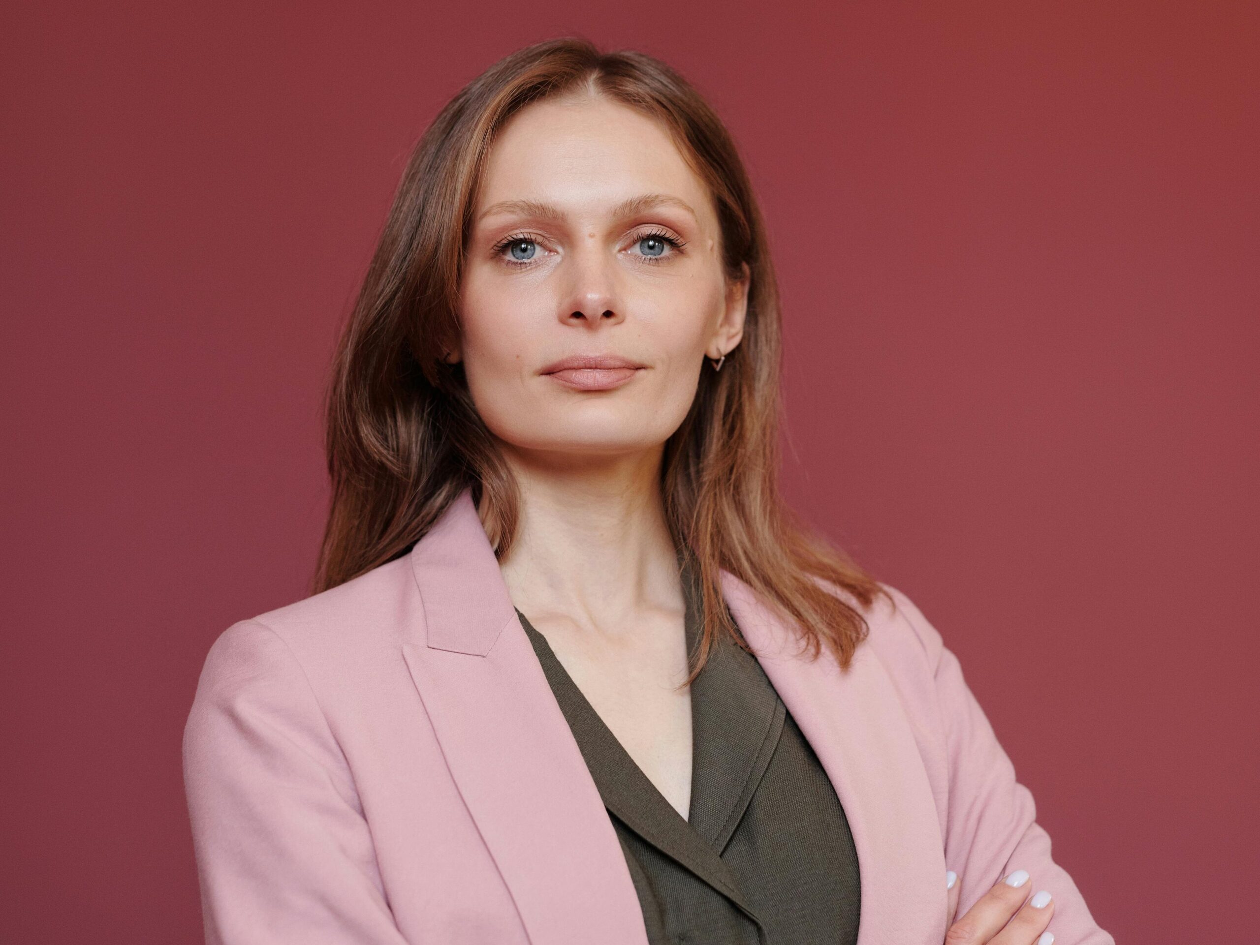 Elegant businesswoman with arms crossed in studio portrait, showcasing leadership and confidence.